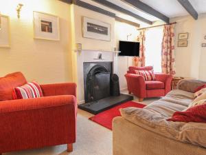 a living room with red chairs and a fireplace at Milkwood Cottage in Fishguard