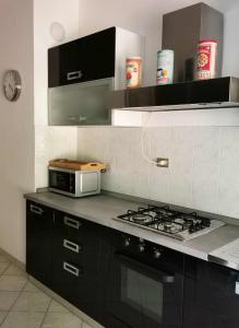 a kitchen with a stove and a microwave at La casa gentile appartamento Aurora in Roccaverano