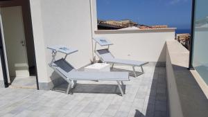 two chairs and a table on the side of a building at Magilù Case con Jacuzzi in Castellammare del Golfo