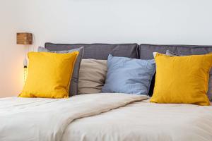 a bed with yellow and blue pillows on it at W4-Rooms EIN ZUHAUSE IM WALDVIERTEL in Allentsteig