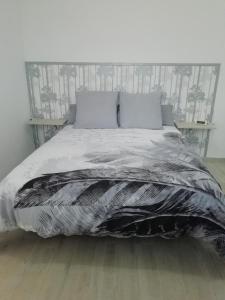 uma cama com um edredão preto e duas almofadas em La Casita del Naranjo em Agüimes