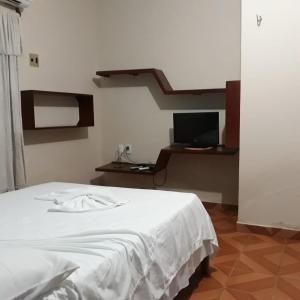 - une chambre avec un lit blanc et un bureau dans l'établissement Pousada Gincoara, à Jericoacoara