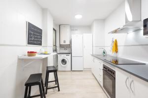 Biała kuchnia z białymi urządzeniami i czarnymi stołkami w obiekcie Mariscal & old town by ELE Apartments w Maladze +8 zdjęć
