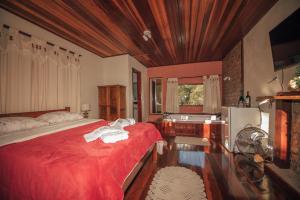 a bedroom with a red bed and a sink at Sítio Recanto do Araçá in Visconde De Maua