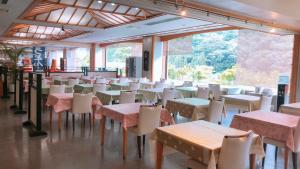 uma sala de jantar com mesas, cadeiras e janelas em Shiobara Onsen Hotel Ohruri em Nasushiobara