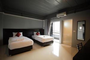 1 dormitorio con 2 camas y ventana grande en B-Black Hotel Chonburi, en Chonburi