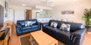 a living room with a black leather couch and a table at Endless Summer Resort in Coolum Beach