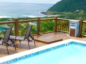 una terraza con piscina, sillas y el océano en Pousada Moradas da Silveira en Garopaba