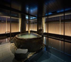 札幌ONSEN RYOKAN Yuen Sapporo的一个大浴缸,位于一个大岩石的房间 更多37张照片