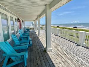 un porche con sillas azules y el océano en Serendipity Shore home, en Crystal Beach