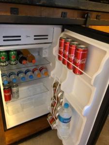 an open refrigerator filled with soda cans and drinks at Chalé de luxo pertinho de Monte Verde in Monte Verde