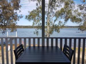 
a wooden bench next to a pier with a view of the water at Pelican Caravan Park in Nambucca Heads
