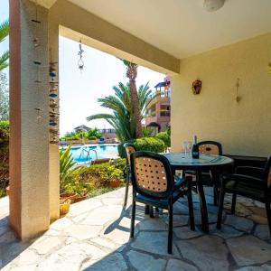 un patio con mesa, sillas y piscina en Tala Hills Sea view apartment en Pafos