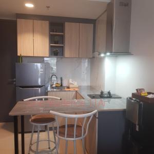 a kitchen with a table and two bar stools at One Residence #11AI in Batam Center