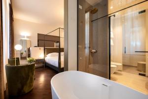 法拉-迪索利戈Hotel Villa Soligo - Small Luxury Hotels of the World的一间带浴缸的浴室和一间带床的卧室