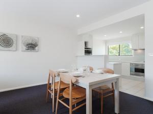 a white kitchen with a white table and chairs at Pacific Blue 245-265 Sandy Point Rd - Dual Key Access, air conditioned unit with resort facilities and linen supplied in Salamander Bay