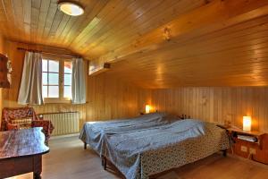 ein Schlafzimmer mit einem Bett und einer Holzdecke in der Unterkunft Les Chélettes in Chateau-d'Oex