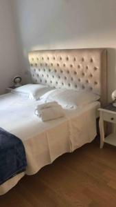 a bedroom with a large white bed with a headboard at Appartamento Ligeia in Bolzano