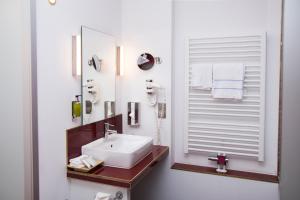 a bathroom with a sink, mirror, and towel rack at Wohlfühlhotel Rabenhorst in Homburg