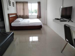a bedroom with a bed and a window and a television at Armthong Resort in Nakhon Nayok