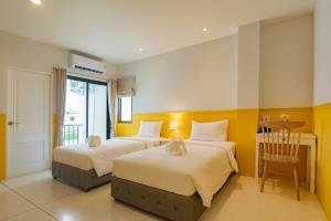 a bedroom with two beds and a table and a chair at Chanita Hotel Chumphon in Chumphon