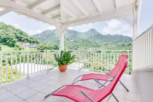 a pink chair on a balcony with mountains in the background at Le Colibri Vert in Le Morne-Vert