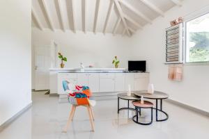 a white kitchen with two tables and a chair at Le Colibri Vert in Le Morne-Vert
