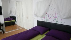 - une chambre avec des lits violets et un mur orné de fleurs dans l'établissement govienna - City Center Apartments, à Vienne