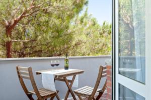 een tafel en 2 stoelen met wijnglazen op een balkon bij [FREE PARKING] Appartamento 5 STELLE elegante con suite in Livorno