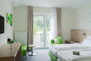 ein Hotelzimmer mit einem Bett und einem Balkon in der Unterkunft aktiv Sporthotel Sächsische Schweiz in Pirna