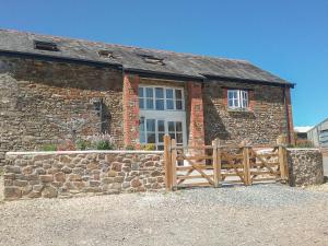 a brick building with a wooden fence in front of it at West Bowden Farm in Knowstone