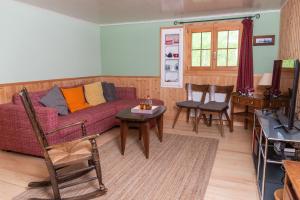 uma sala de estar com um sofá roxo, uma mesa e cadeiras em Chalet le Petit Tremplin em Leysin