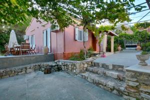a pink house with a stone wall and a patio at Jerry Afro in Kanálion
