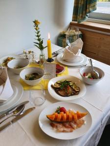 una tavola con piatti di cibo e una candela di Natur Pur Hotel Unterpichl a Ultimo
