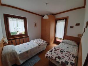 a bedroom with two beds and two windows at Appartamento al Pelmo in Villanova