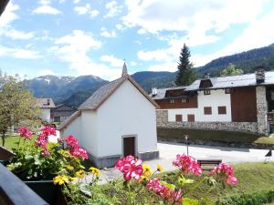 ein kleines weißes Gebäude mit Blumen davor in der Unterkunft Appartamento al Pelmo in Villanova