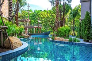 una piscina en un complejo con palmeras en The Apartment at The Title Residencies Naiyang Beach en Phuket