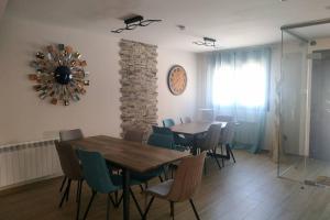 a dining room with a table and chairs and a clock on the wall at La Olma in Campillo de Aranda