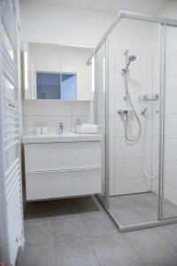 ein weißes Bad mit einem Waschbecken und einer Dusche in der Unterkunft Alpine Chalet Ulla Top 3 by AA Holiday Homes in Bad Mitterndorf
