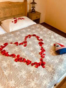 ein Herz aus roten Rosenblättern auf einem Bett in der Unterkunft U Námořníka-Restaurant a penzion in Hukvaldy