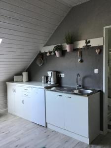 a kitchen with white cabinets and a sink at Apartment am Park -Calluna in Schneverdingen