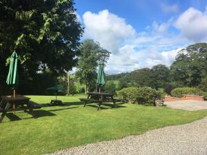 two picnic tables with umbrellas in a park at Arden House Hotel in Kirkcudbright