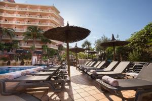 een rij ligstoelen en parasols naast een zwembad bij Hotel Alba Seleqtta in Lloret de Mar