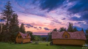 due cabine di legno in un campo con un tramonto di les Refuges du Chalet a Sart-lez-Spa