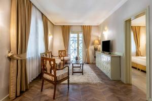 a living room with a bed and a television and chairs at Polat Thermal Hotel in Pamukkale