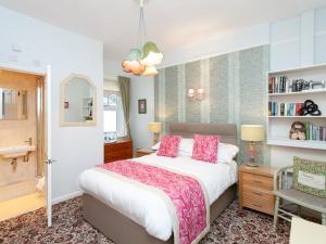 um quarto com uma cama grande e almofadas cor-de-rosa em The Ravenswood B&B em Torquay