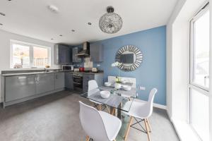 a kitchen with blue walls and a table and chairs at Royal House Wolverhampton - Perfect for Contractors & Large Groups in Wolverhampton