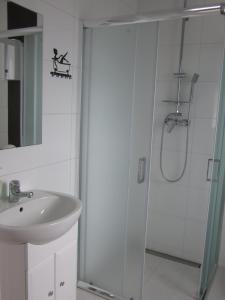 a white bathroom with a shower and a sink at Morskie Zacisze in Łeba
