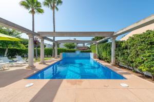 a swimming pool in a backyard with palm trees at Estrel in Can Picafort