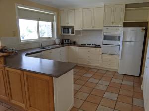 a kitchen with a stove, refrigerator, sink and dishwasher at Shearwater Cottages in Port Sorell